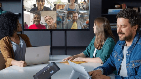 teams-three-people-in-a-conference-room-engaged-in-a-teams-meeting-displayed-on-a-large-monitor-with-another-group-of-people-who-are-all-in-different-locations-interstellar-business-solutions-limited-ibsl