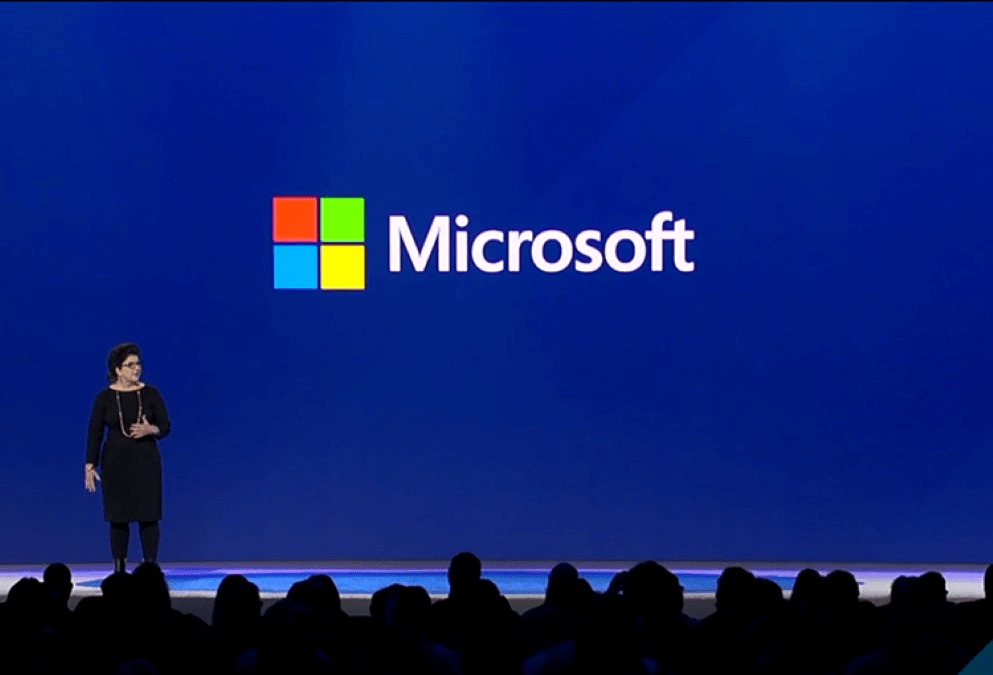 photograph-of-a-person-standing-in-front-of-a-large-microsoft-logo-speaking-to-a-large-audience-interstellar-business-solutions-limited-ibsl