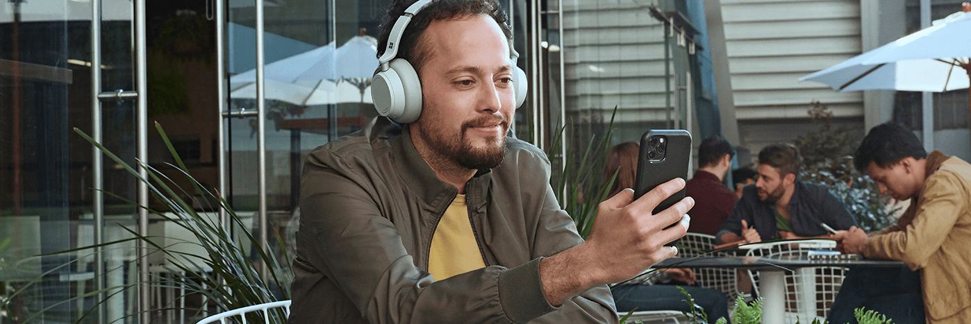 teams-person-with-headphones-looking-at-a-mobile-device